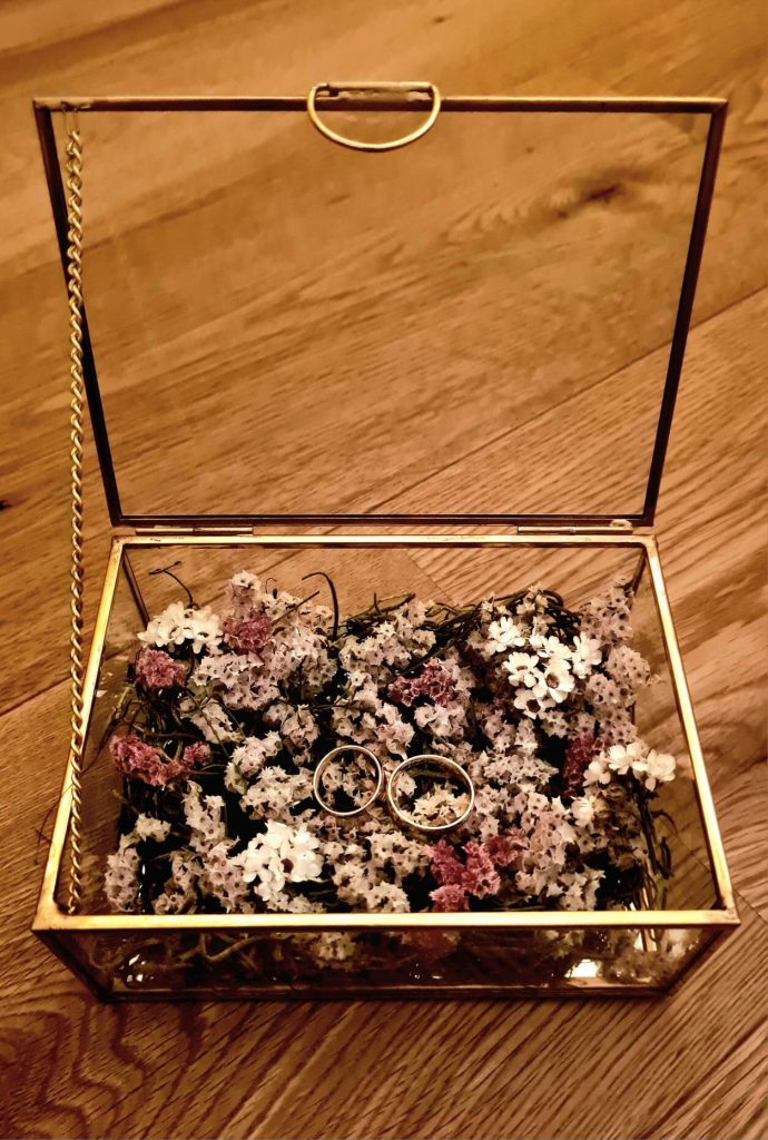 Foto de alianzas de boda de oro en caja de cristallo con borde Dorado y Flores. Elopement