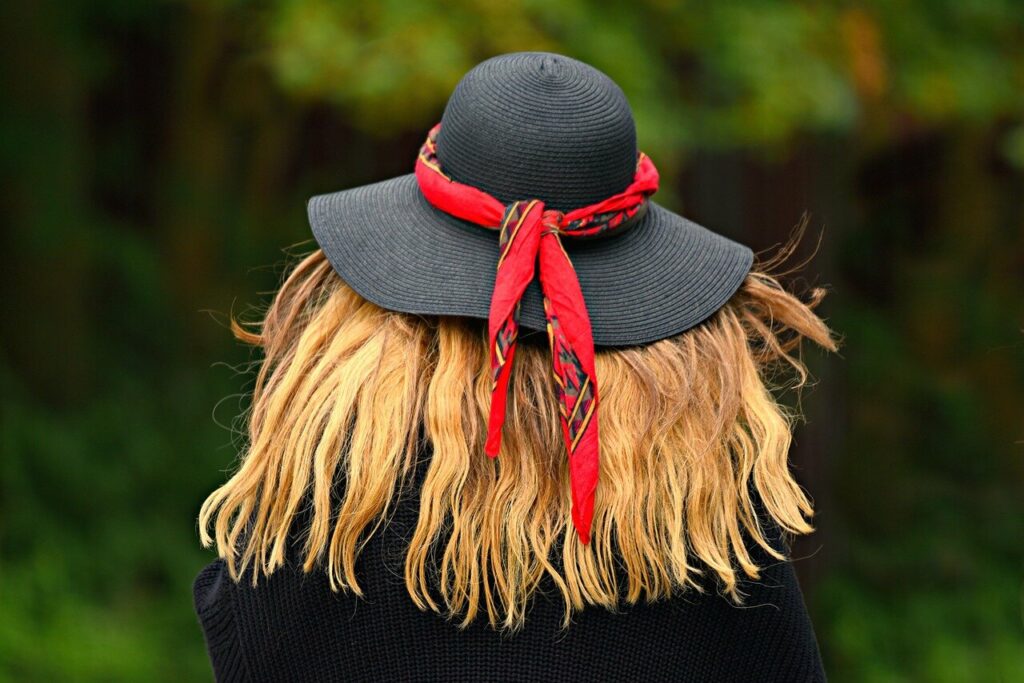Foto de mujer de espaldas, con cabello rubio y sombrero negro y rojo